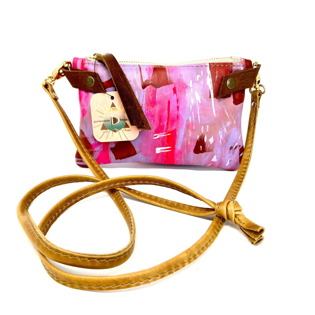 Woman holding brown and pink floral leather crossbody bag photo